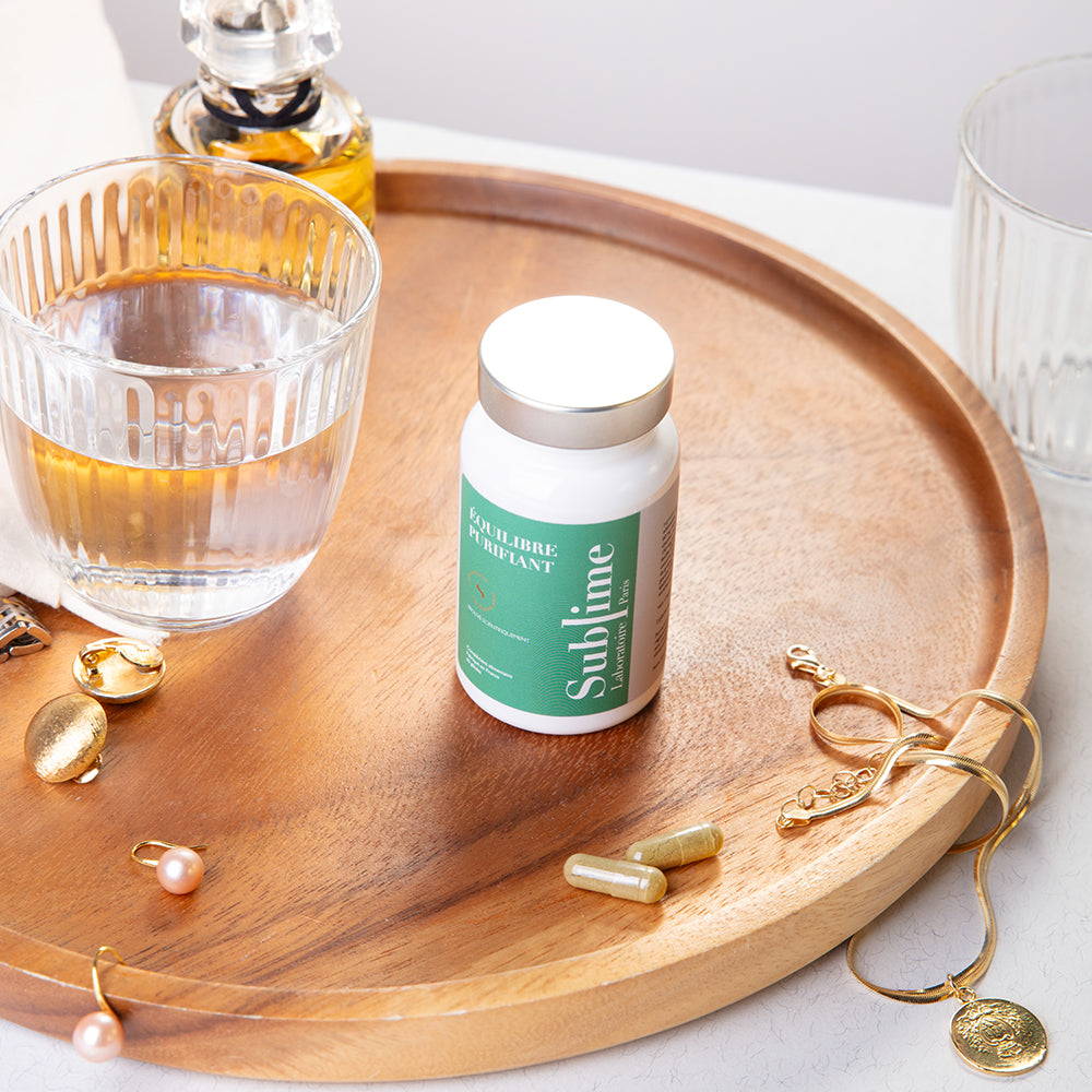 Laboratoire Sublime Purifying Balance detox supplement bottle with capsules and jewelry, French liver and skin detox formula, upward angle view lifestyle background
