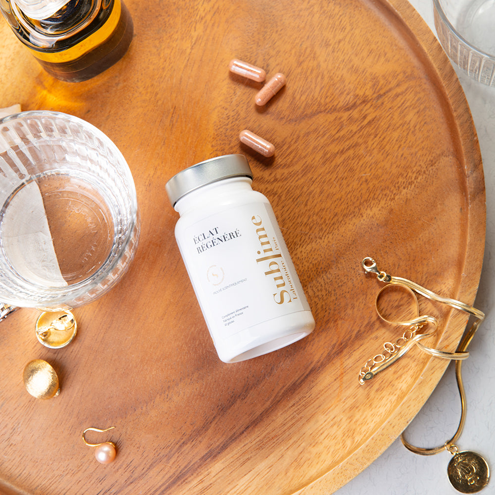 Laboratoire Sublime Regenerated Radiance supplement bottle with capsules and jewelry on wooden tray, French antioxidant and UV-protection supplement, flat lay lifestyle view