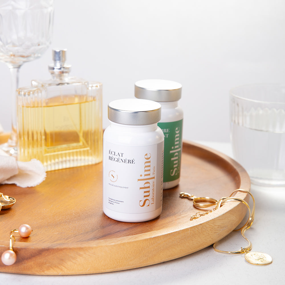 Laboratoire Sublime Regenerated Radiance and Purifying Balance supplement bottles with jewelry and glassware, French antioxidant and detox beauty supplements, front view lifestyle background.