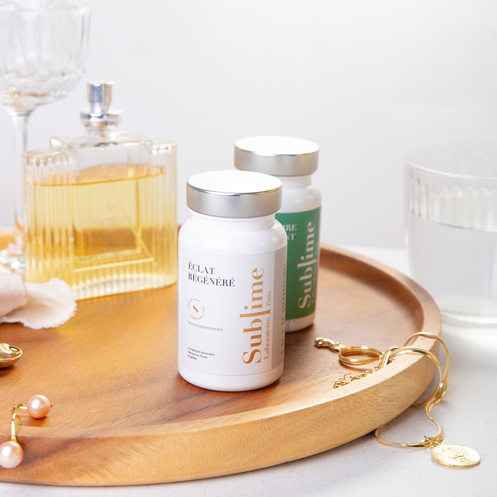 Laboratoire Sublime Regenerated Radiance and Purifying Balance beauty supplements displayed on a wooden tray with gold jewelry, glass, and perfume bottle, representing elegant French skincare nutrition.