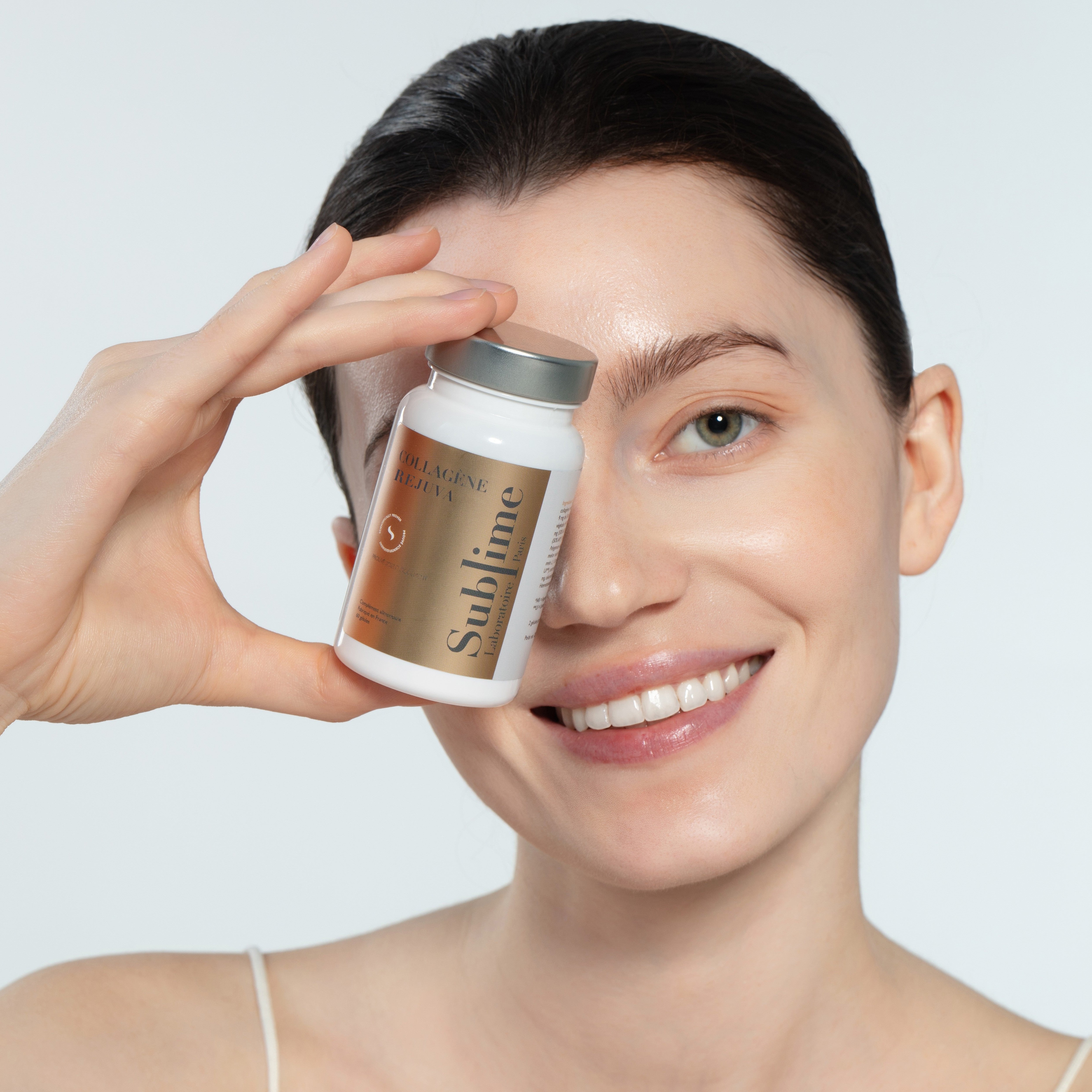 Woman holding Laboratoire Sublime Rejuva Collagen supplement bottle, collagen beauty supplement for radiant skin, front portrait view.